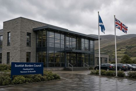 Scottish Borders Council headquarters in Newtown St Boswells on an overcast day, with council signage and flags outside the office building.
